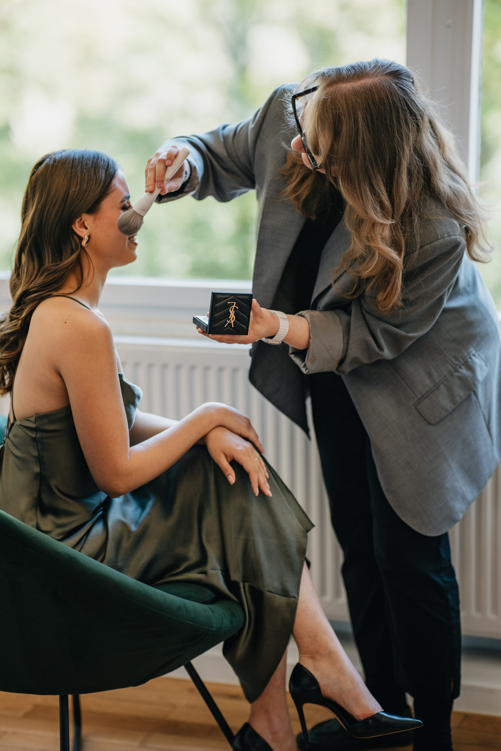 Make-up-Artistin Jana Festag vollendet das Gästestying mit Puder und Pinsel bei einer Hochzeit in Düsseldorf
