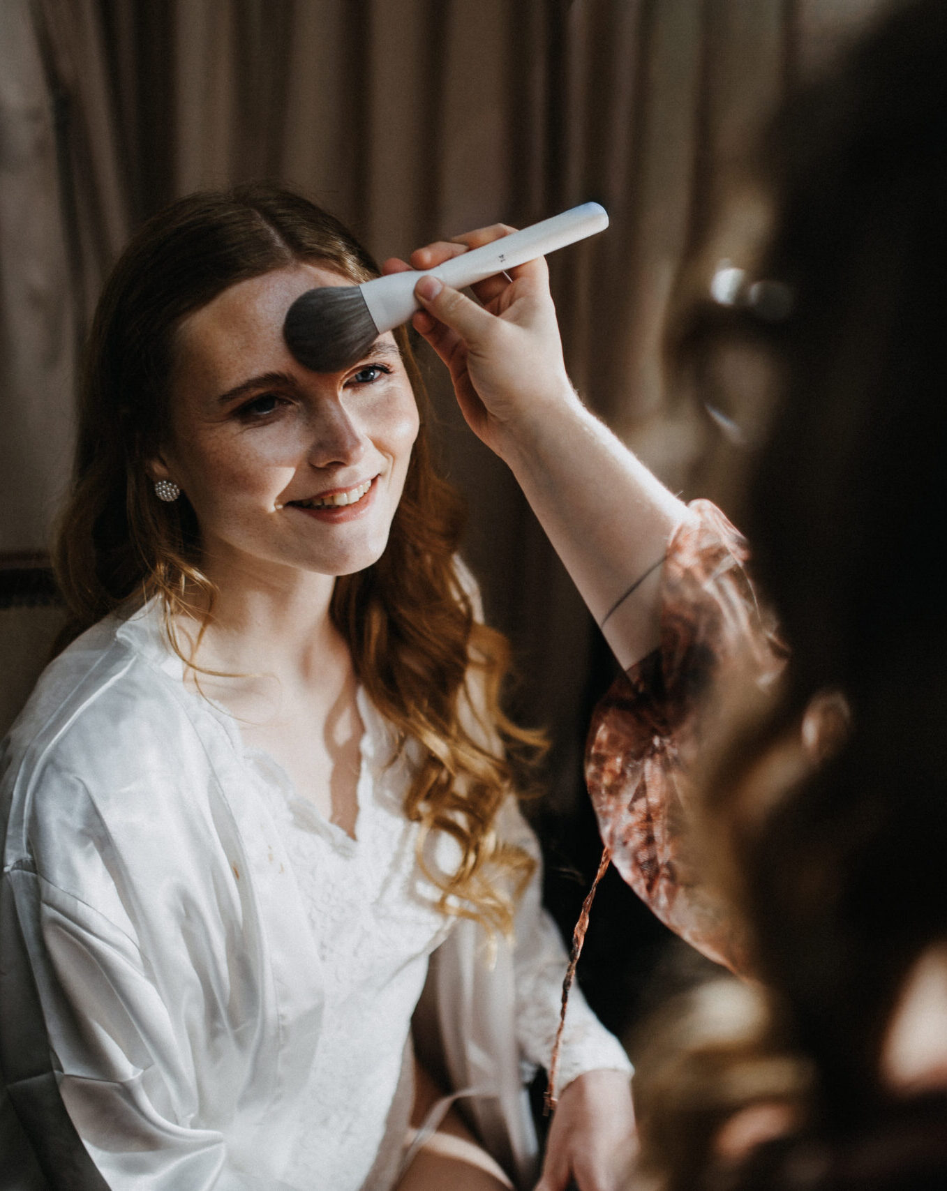 Make-up-Artistin Jana Festag schminkt eine lächelnde Braut beim entspannten Brautstyling in Düsseldorf