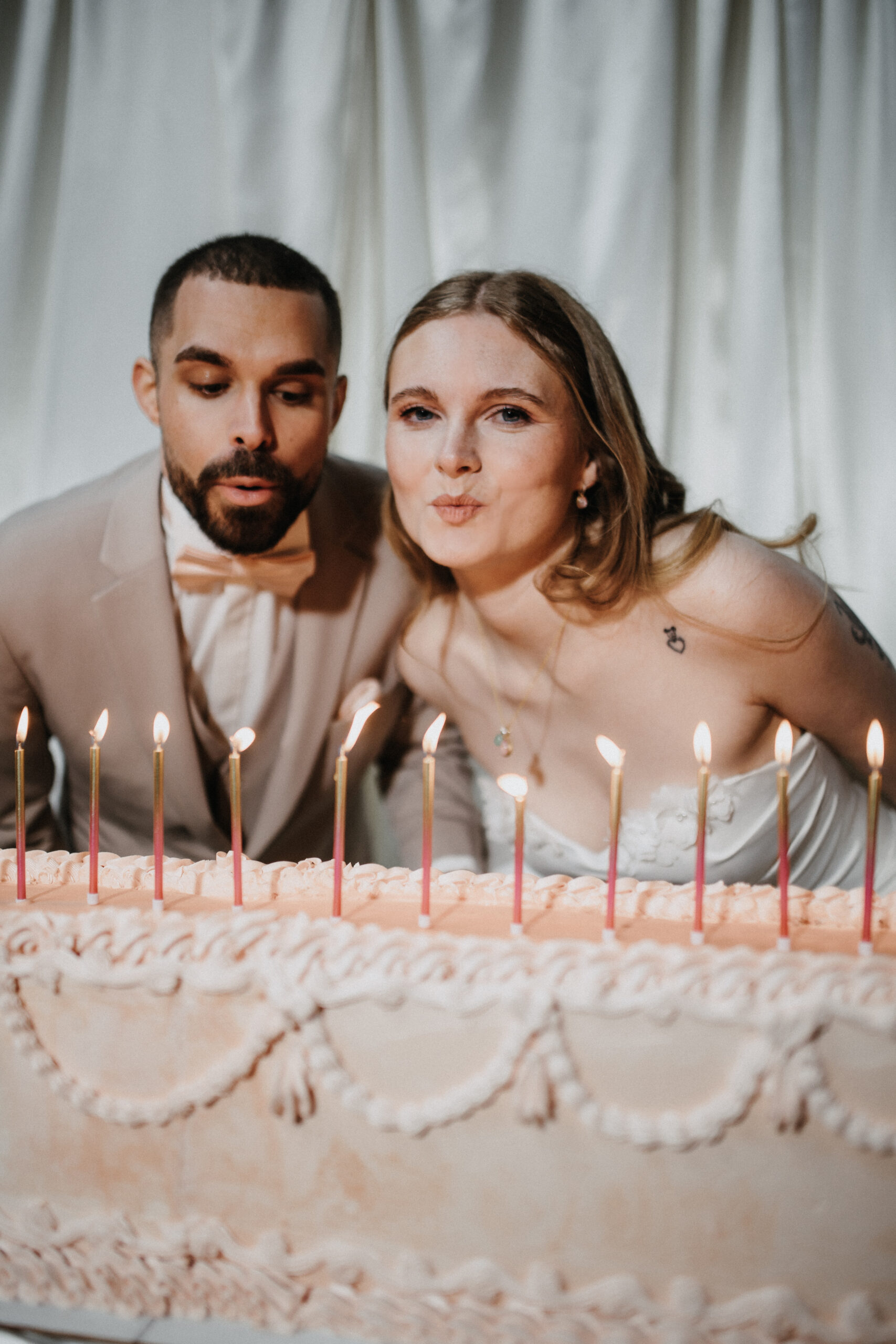 Braut und Bräutigam vor der Hochzeitstorte nach dem eleganten Brautstyling von Jana Festag in Düsseldorf