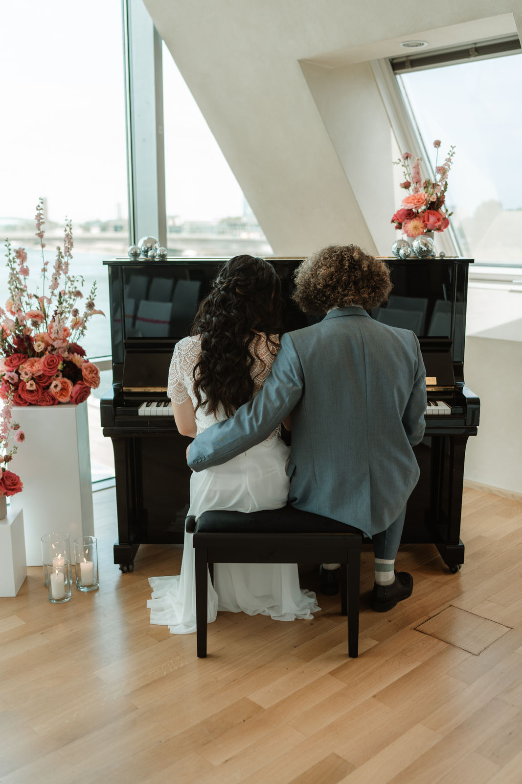 Brautpaar sitzt gemeinsam vor einem Klavier bei einer Hochzeit in NRW – Brautstyling von Jana Festag